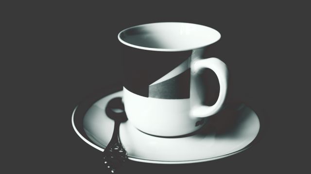 This close-up black and white image features a coffee cup adorned with an abstract geometric design, accompanied by a spoon and saucer. The minimalist and modern aesthetic makes this image ideal for use in blogs, websites, and social media posts related to coffee culture, interior design, or modern art. It can also be used in marketing materials for cafes or coffee shops to convey an elegant and stylish atmosphere.