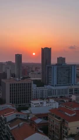 Sun descending behind highrise skyline during orange dusk vertical city sunset video