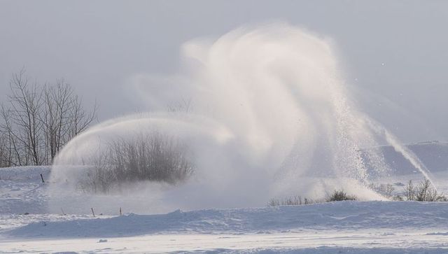 Swirling snow plume over rural field creating glowing mist and frozen motion