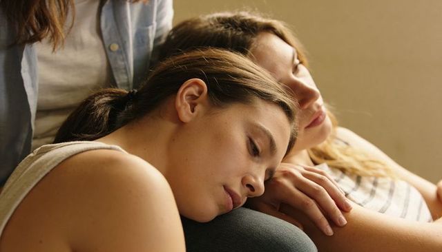 Two women resting together on sofa sharing intimate cozy moment of calm and togetherness