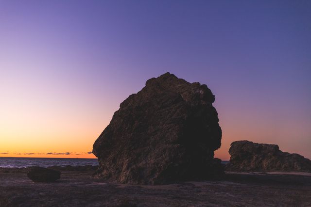 Impressive rock formations silhouetted against a beautiful sunset at a tranquil beach. Ideal for use in travel brochures, nature magazines, desktop wallpapers, and interior decor. Perfect for promoting coastal destinations, inspiring relaxation, or adding a touch of natural beauty to any project.