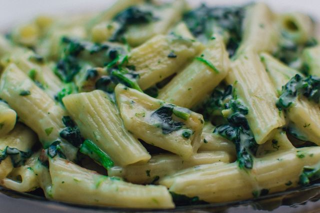 Penne noodles mixed with a creamy spinach sauce, perfect for illustrating healthy recipes, vegetarian meals, or Italian cuisine blog posts and cookbooks.