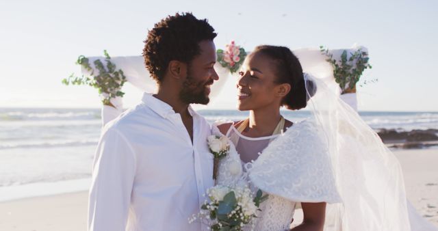 Portrait of african american couple in love getting married and smiling to camera on the beach. marriage, love and romance, holiday by the sea.