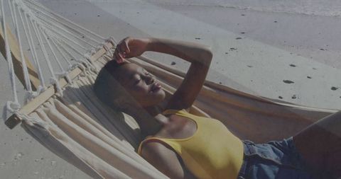 Woman relaxing in hammock on serene beach