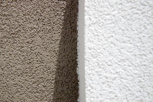 Textured surfaces of two walls, one brown and one white, separated by a shadowed crease. Ideal for themes emphasizing architecture, contrast, and building materials. Useful in design projects, construction site presentations, and educational materials on wall textures and finishes.