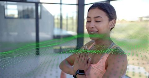 Sunlit woman practicing mindfulness with smartwatch and green digital data overlay