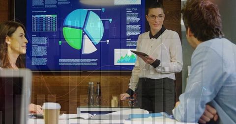 Businesswoman presenting interactive pie chart on digital dashboard during team meeting