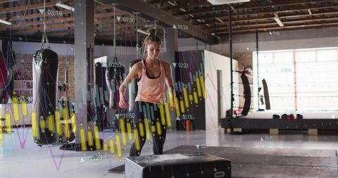 Female athlete jumping onto plyo box in modern gym with performance data overlay