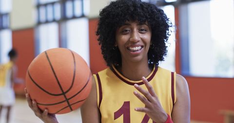 Smiling Female Basketball Player Holding Ball on Indoor Court