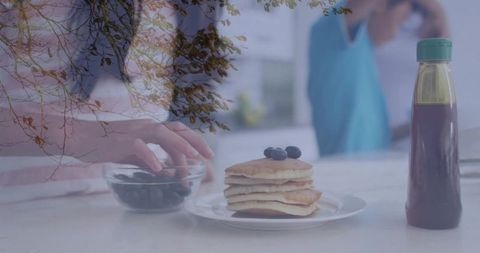 Blueberry Pancake Stack with Hand Reaching into Bowl and Tree Branch Overlay