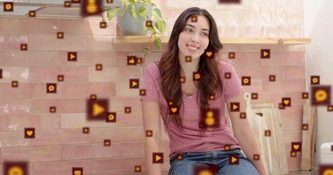Young woman sitting in pink kitchen with floating social icons for online engagement