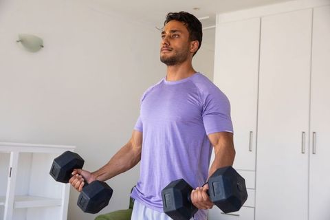 Athletic Man Lifting Dumbbells in cozy Home Gym Setting