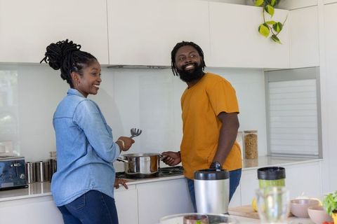 African american couple cooking together in modern kitchen sharing smiles and meal prep