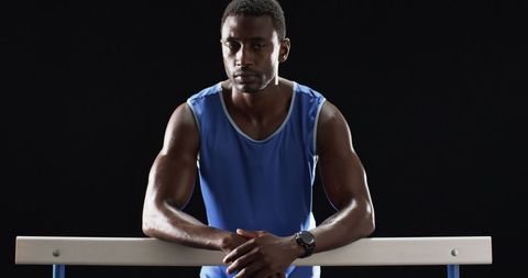 Focused Athlete in Blue Tank Top Resting on Hurdle - Download Free Stock Images Pikwizard.com
