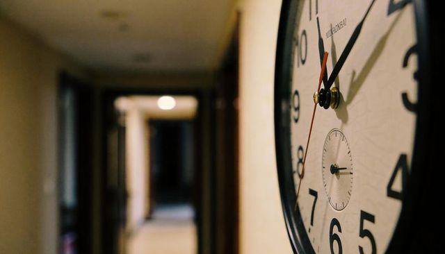 Close-up analog wall clock in hallway showing time with warm ambient lighting