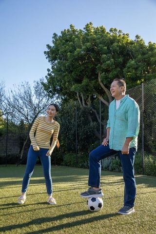 Happy Couple Enjoying Outdoor Soccer Game in Sunlit Yard