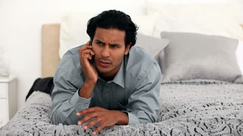 Man Engaged in Phone Conversation on Comfortable Bed