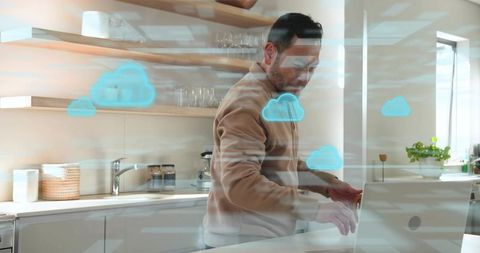 Asian man working on laptop in modern kitchen showing cloud computing and remote work