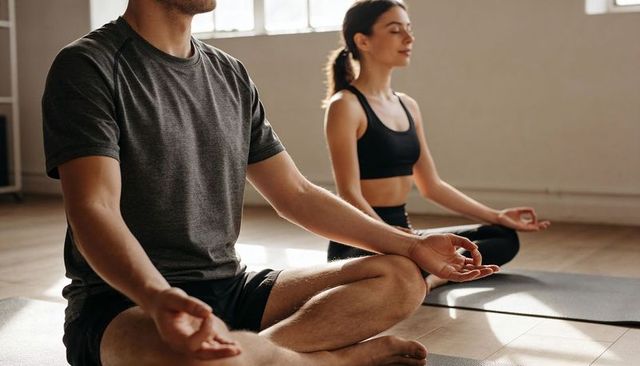 Couple practicing seated meditation on yoga mats in sunlit minimalist studio