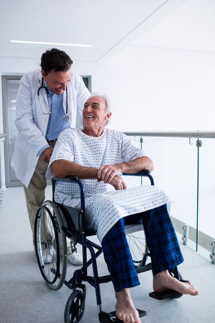 Doctor interacting with male senior patient on a wheelchair in the passageway at hospital