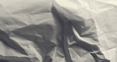 Crumpled sheet of white paper in close-up view, showcasing intricate creases and subtle shadows. Perfect for users looking to enhance design projects, create artistic backgrounds, or incorporate unique textures into presentations and digital art.