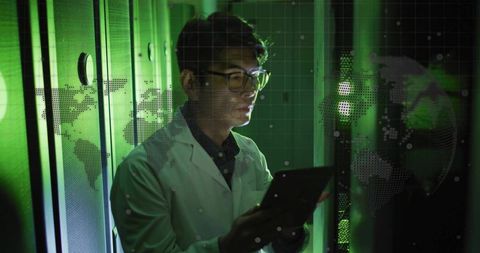 Korean IT engineer monitoring server racks holding tablet in green-lit datacenter