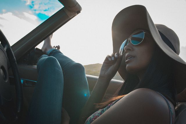 Biracial woman wearing sun glasses looking sitting in convertible car - Download Free Stock Photos Pikwizard.com