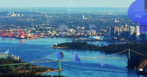 Spanning green suspension bridge crossing blue harbor with forested peninsula skyline