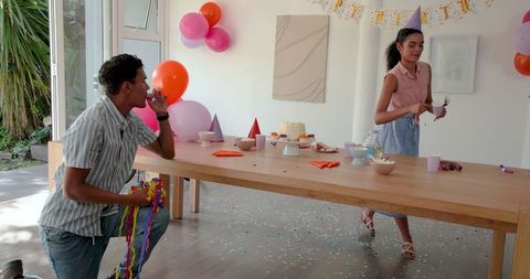 Joyful couple preparing for festive celebration with cake and party decorations