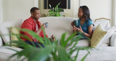 Smiling Couple Relaxing with Coffee on Living Room Sofa