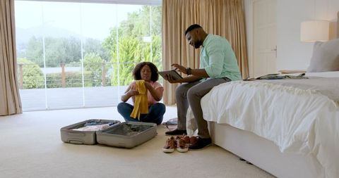 Couple Packing for Romantic Getaway in Bright Bedroom