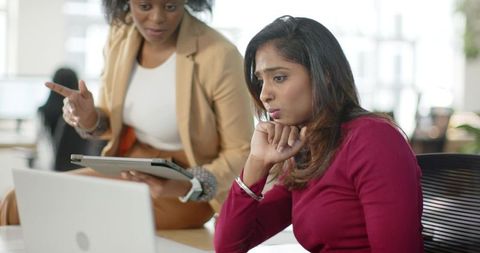 Diverse Colleagues Collaborating Over Laptop and Tablet in Bright Modern Open Office