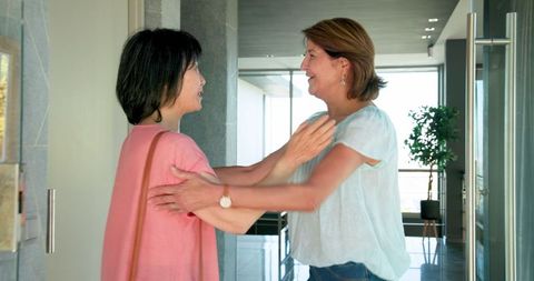 Senior Women Embracing at Home Entrance in Warm Interaction