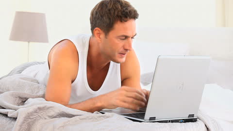 Man Frustrated with Laptop While Lying in Bed