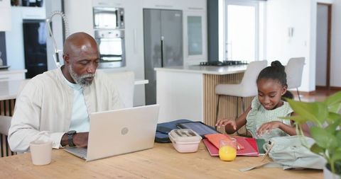 African American Father Working from Home While Daughter Organizing School Papers