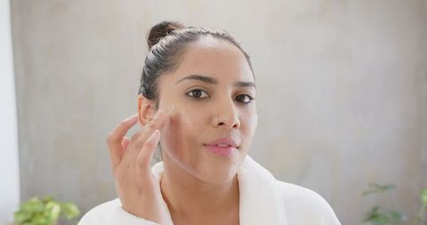 Woman in Bathrobe Applying Face Cream in Peaceful Setting