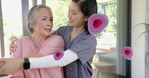 Home caregiver guiding senior woman through stretching exercise with smartwatch support