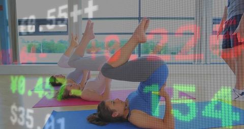 Group performing bridge pose in modern fitness class with digital market ticker overlay