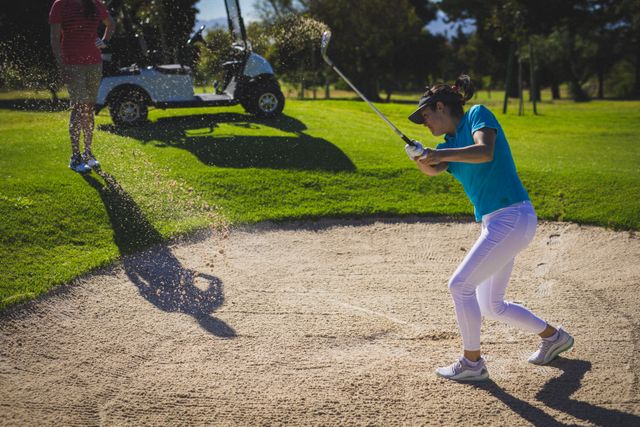 Caucasian woman hitting golf ball out of sand trap at golf course. sports and active lifestyle concept.
