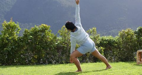 Woman practicing yoga side stretch outdoors in mountain scenery