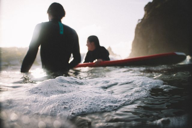 Surfers entering ocean at sunset with surfboards - Download Free Stock Images Pikwizard.com