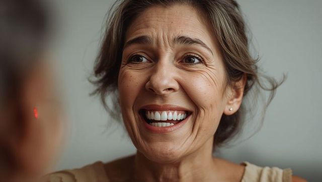 Mature woman smiling warmly with natural laugh lines closeup for dental and wellness