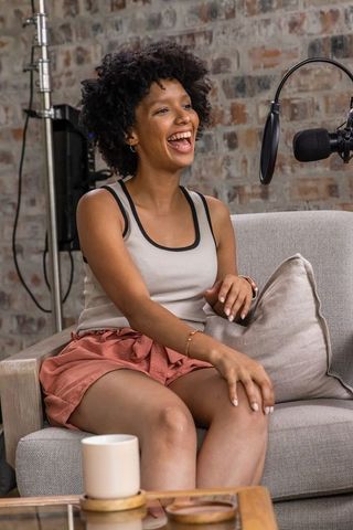 Laughing african american woman recording podcast in cozy brick loft studio conversation