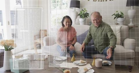 Smiling senior couple enjoying pastries on sofa while interacting with holographic display