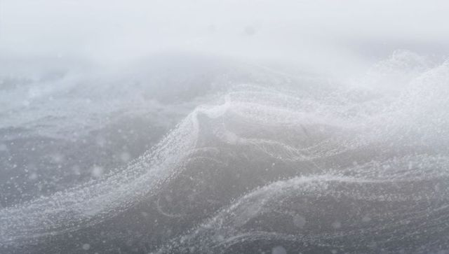 Braided sea foam rolling over low ocean waves in misty monochrome horizon, suspended air bubbles