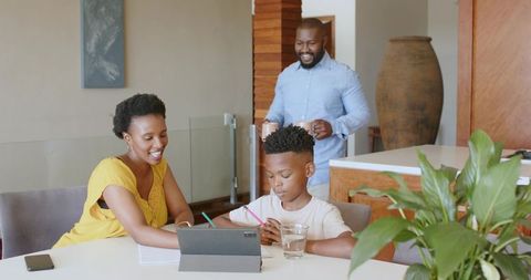 African American family studying together at modern kitchen table using tablet