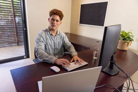 Man typing at home office desk with modern tech and minimalist decor