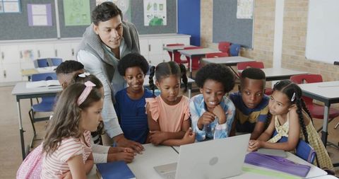 Teacher Guiding Diverse Elementary Students Using Laptop for Collaborative Learning