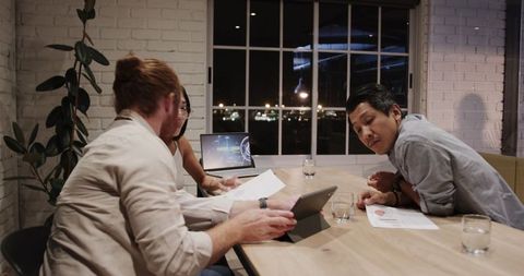 Night office collaboration among diverse professionals with digital devices
