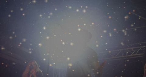 Lead vocalist singing on hazy concert stage with sparkling light bokeh and silhouette